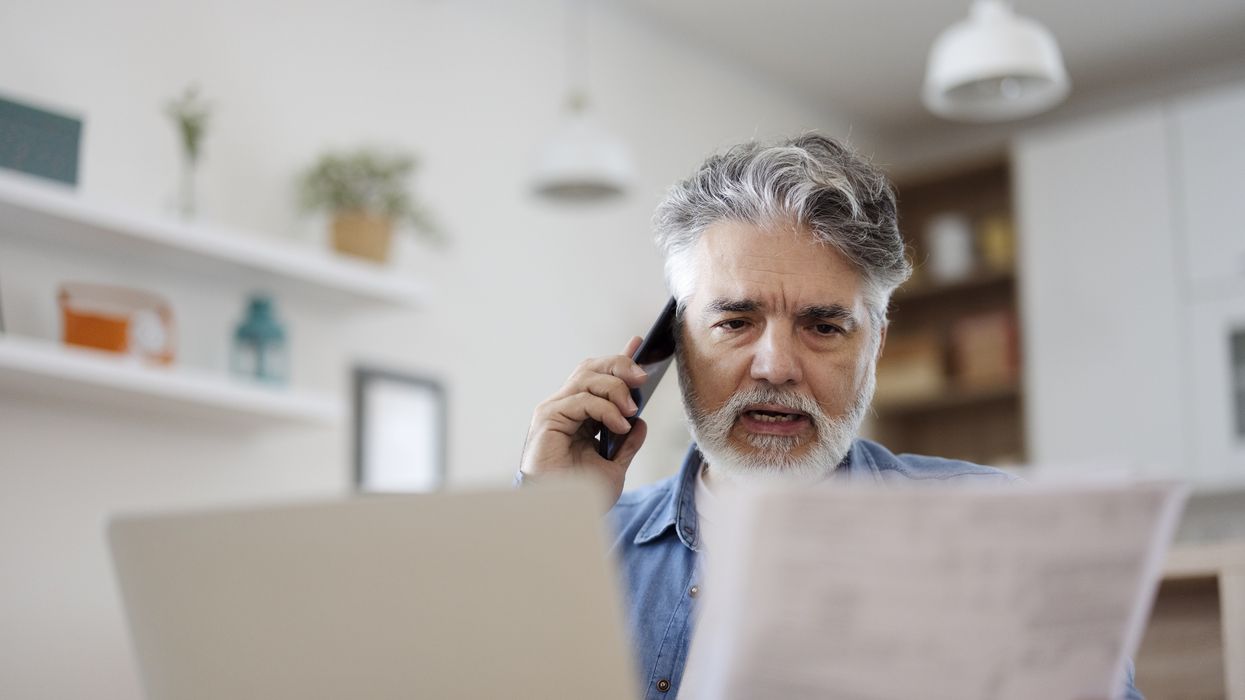 Person looks at letter while on the phone