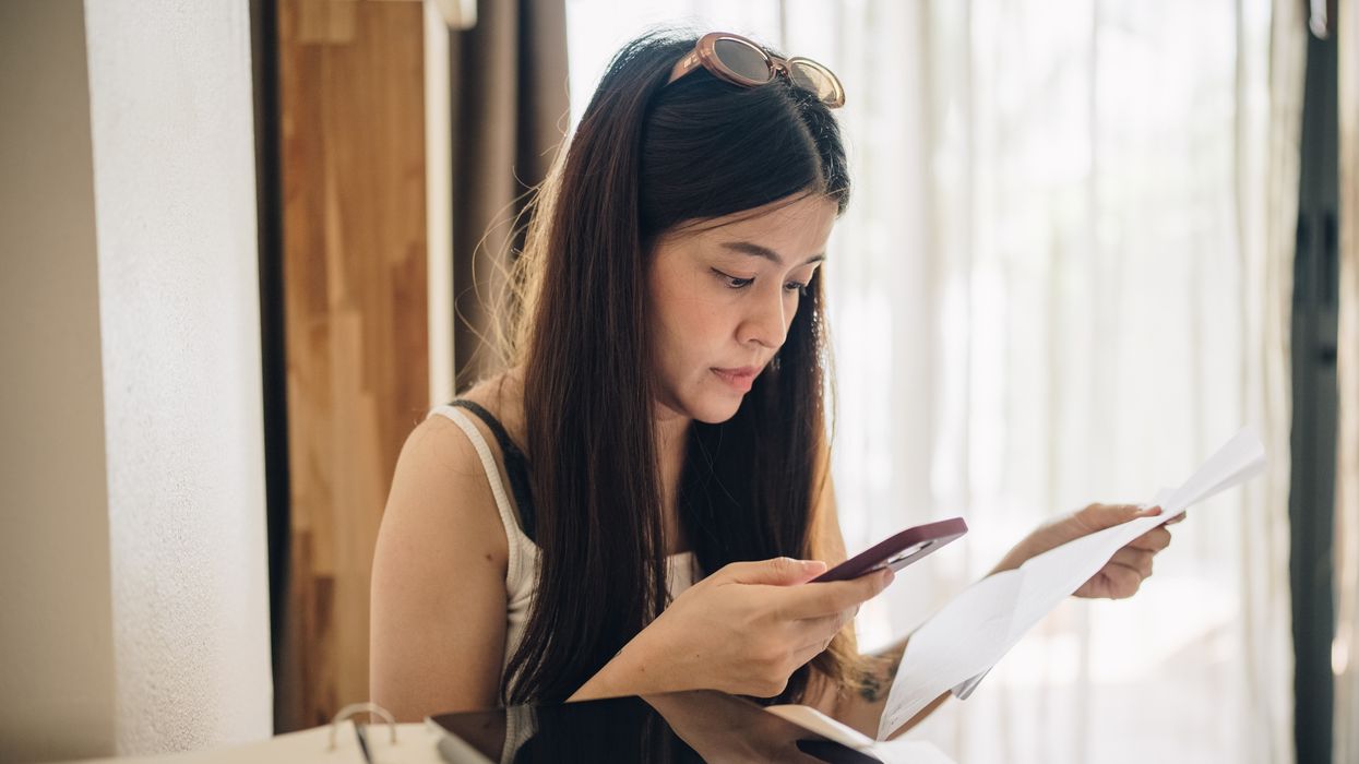 Person looks at phone and letter