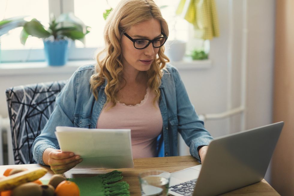 Person looks at water bill statement and laptop