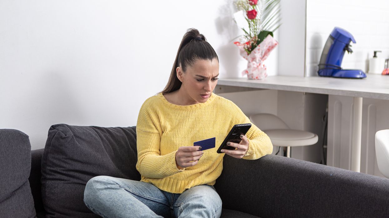 Person looks worried at phone with card in hand