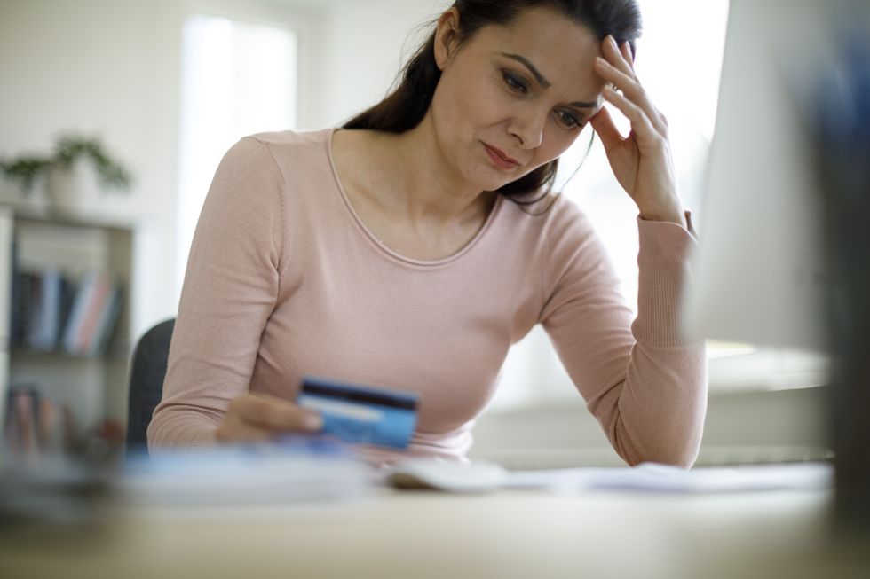 Person looks worried while holding bank card