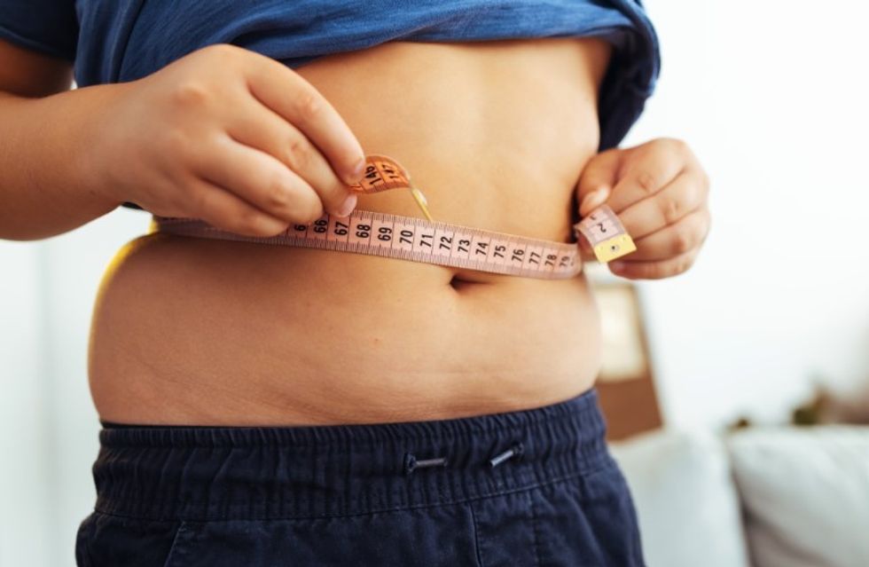 PERSON MEASURING THEIR BELLY FAT