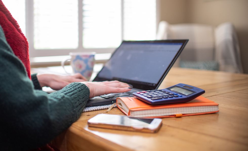 Person on laptop sitting beside notepad and calculator