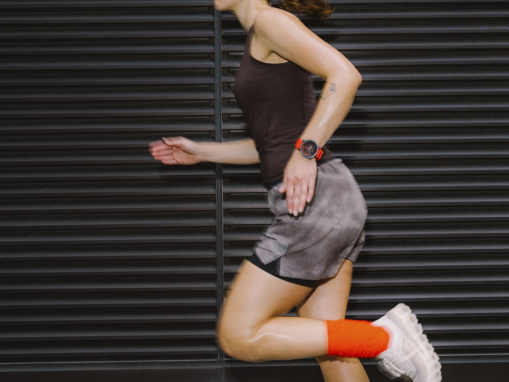 person pictured running with the Watch 3 Pro from CMF by Nothing in orange and black on their wrist