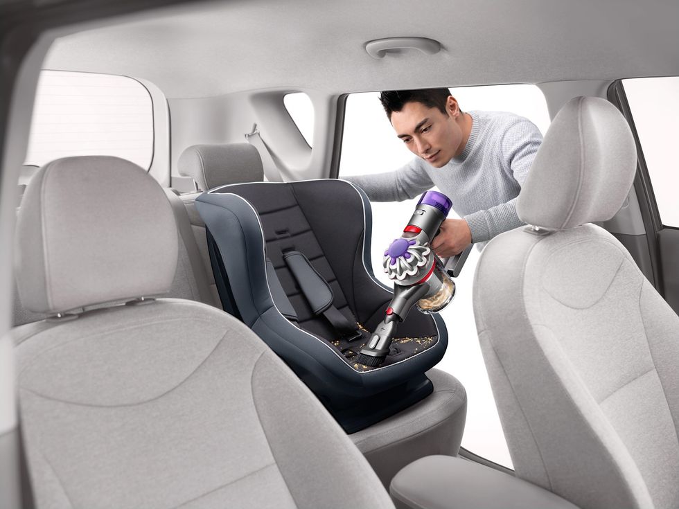 person pictured vacuuming the inside of a car seat with the car plus boat