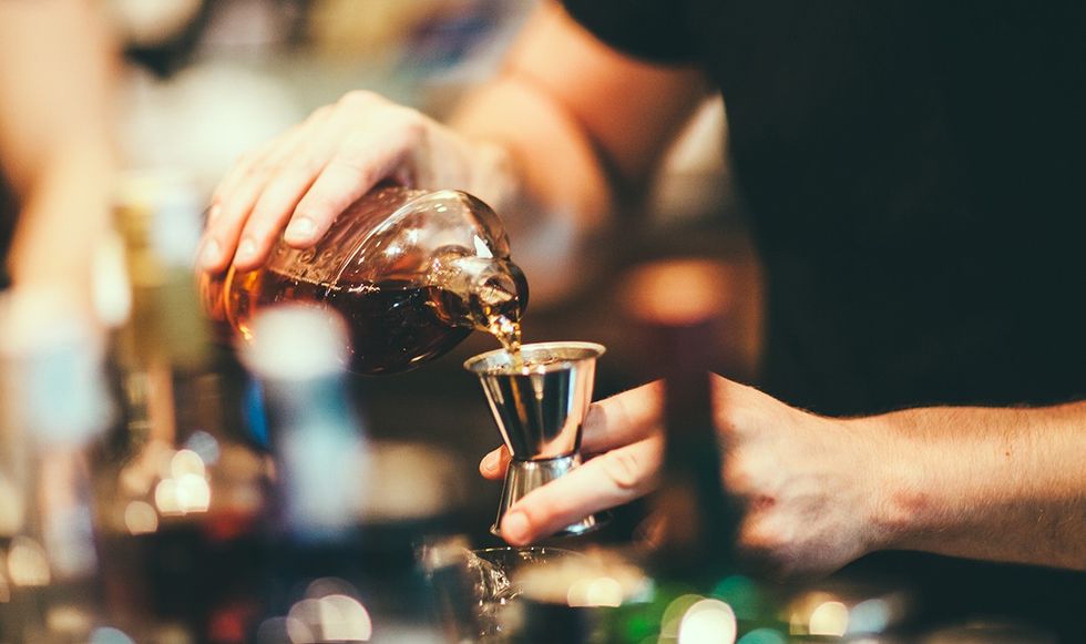 Person pouring alcohol into a shot cup