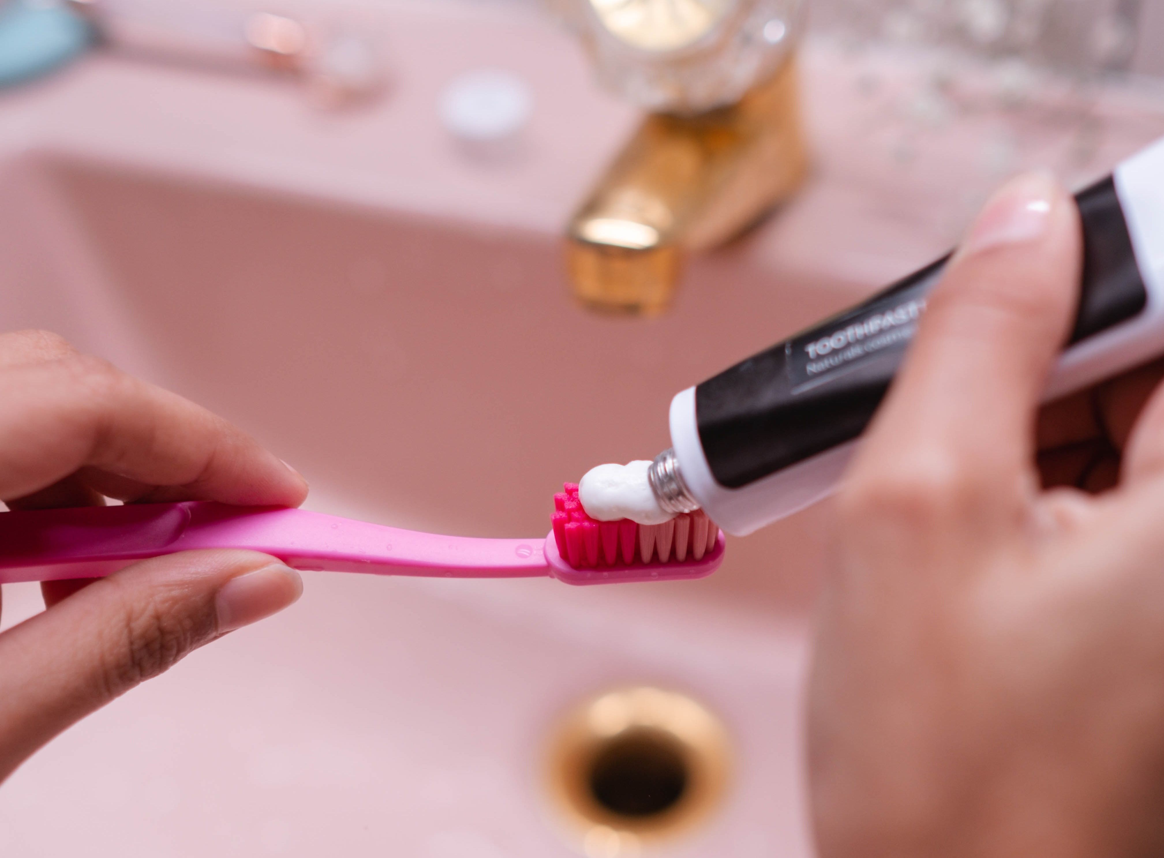 Person putting toothpaste on a toothbrush