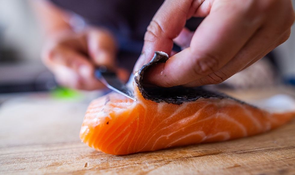 Person removing salmon skin with a knife