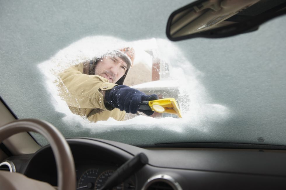 Person scraping frost from windscreen