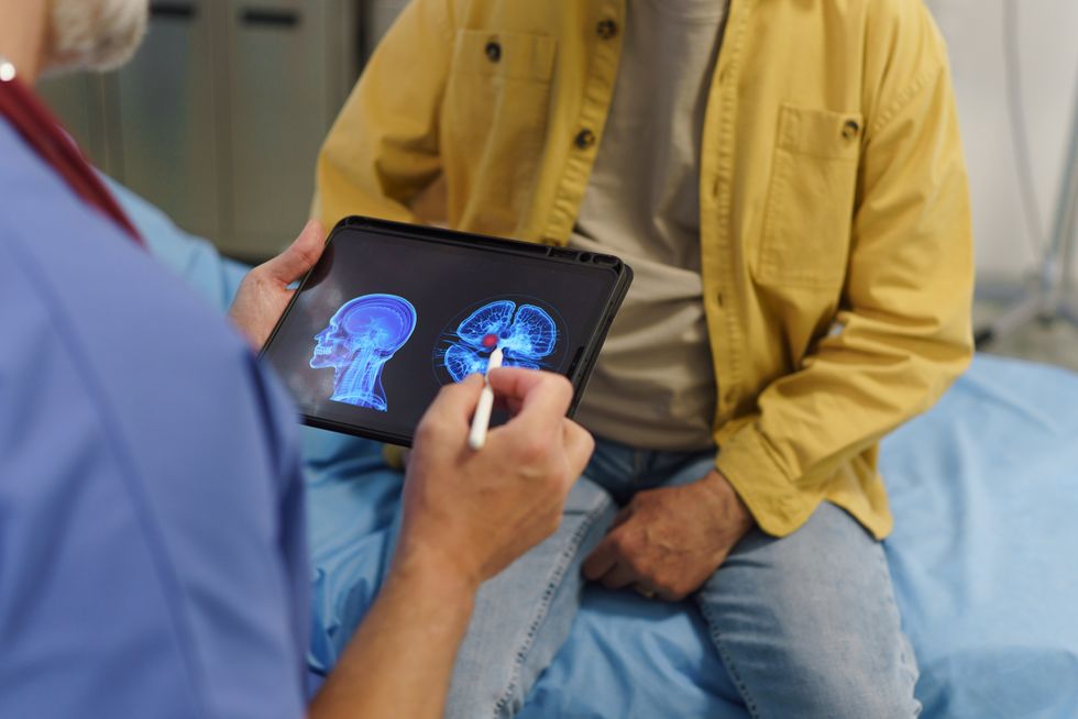 Person sitting on a bed while a medic assesses brain scans