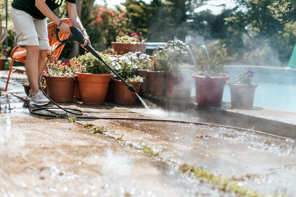 Person using a pressure washer in a garden