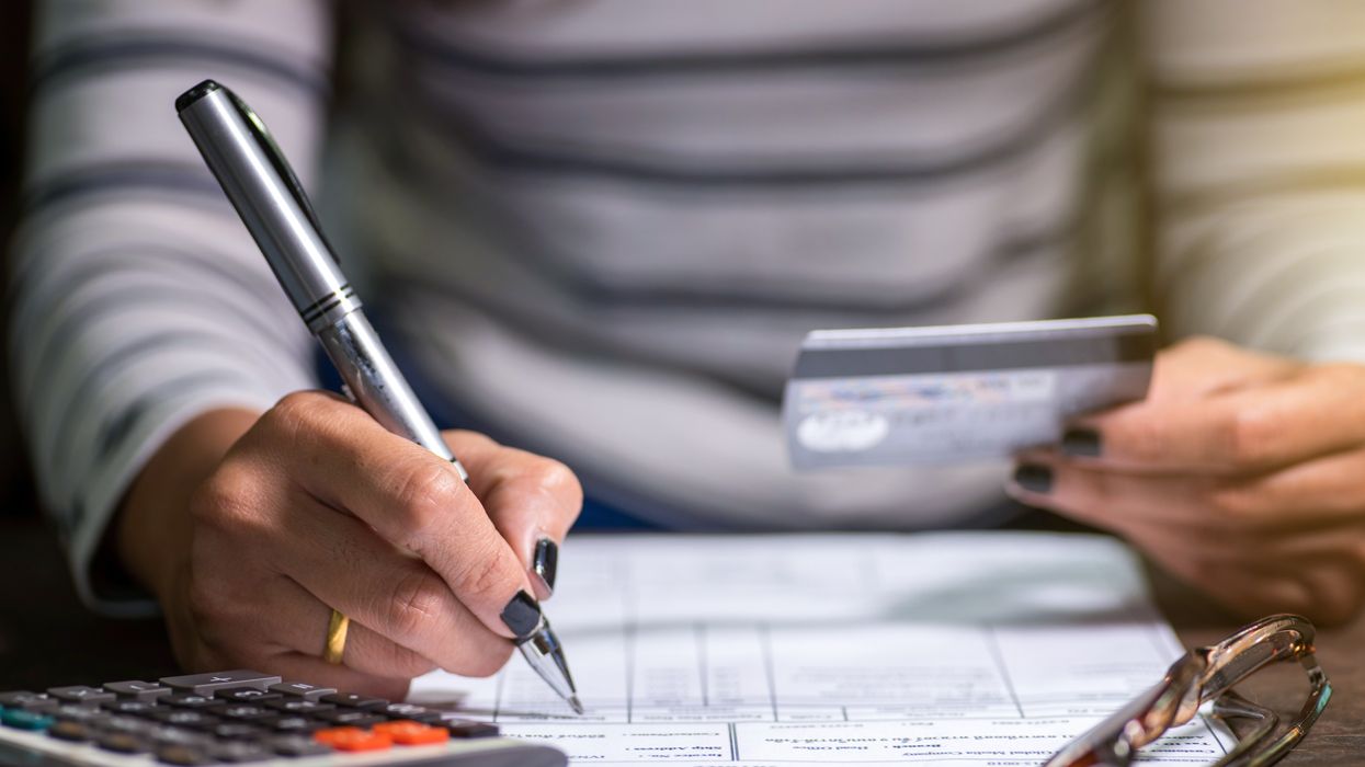 Person using calculator and holding debit card