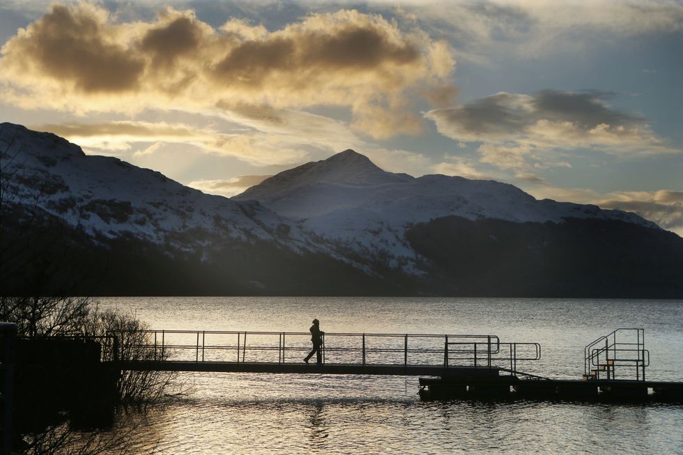 Person walking across bridge in front of Ben Lomond, Loch Lomond
