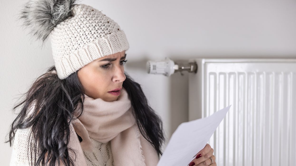 Person wears warm hat and looks at energy bill statement during very cold weather