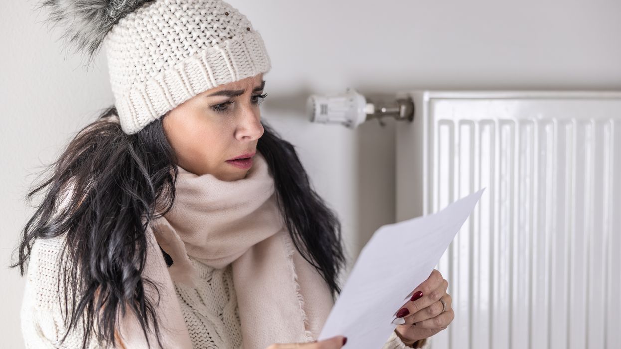 Person wears warm hat and looks at energy bill statement during very cold weather