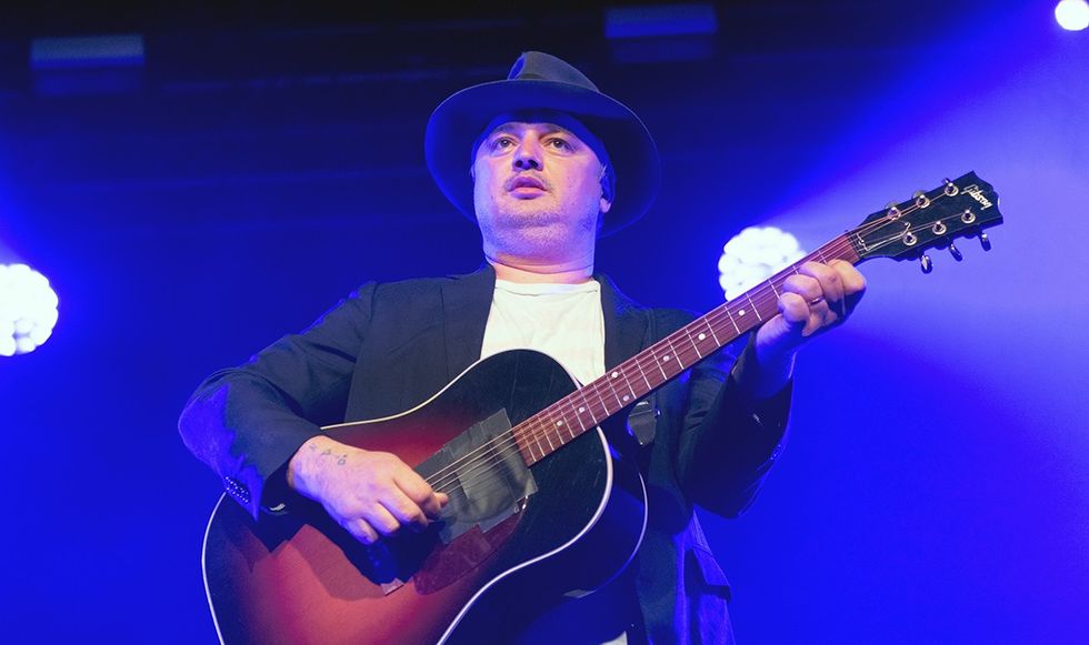Pete Doherty playing his guitar on stage
