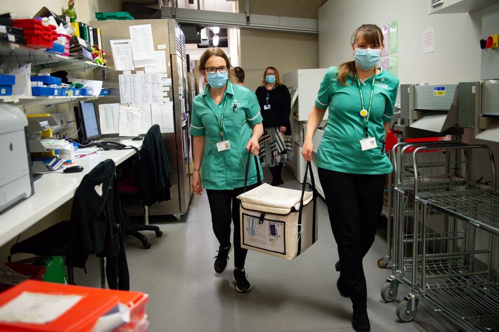 Pharmacists transport a cooler containing the Moderna vaccine, at the West Wales General Hospital in Carmarthen