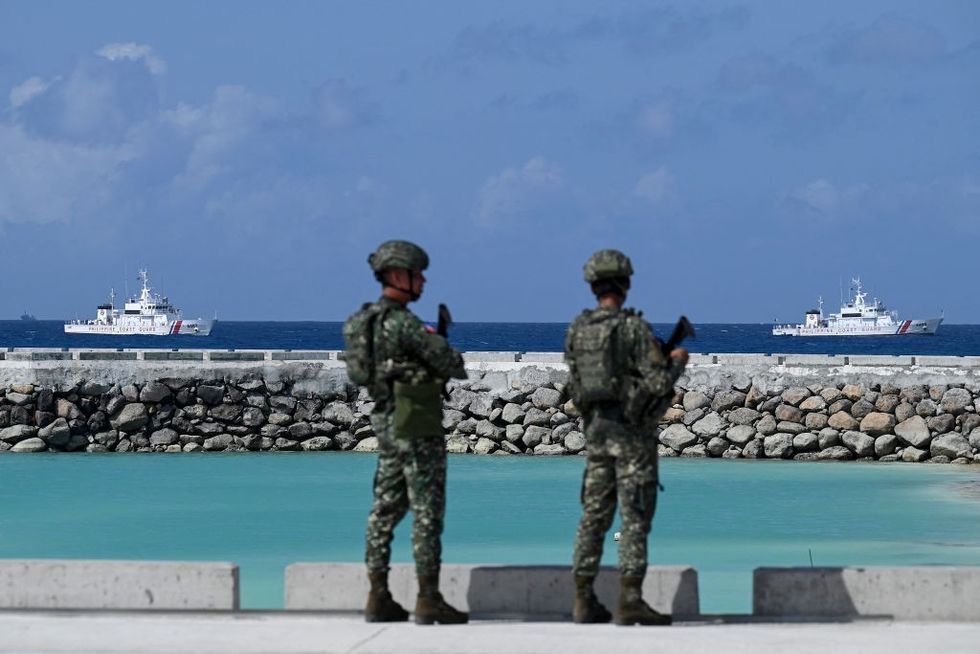 Philippine soldiers look at Philippine Coast Guard vessels near Thitu Island