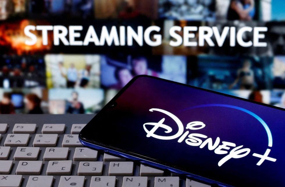 Phone screen displaying Disney+ in front of a laptop showing the text 'streaming service'