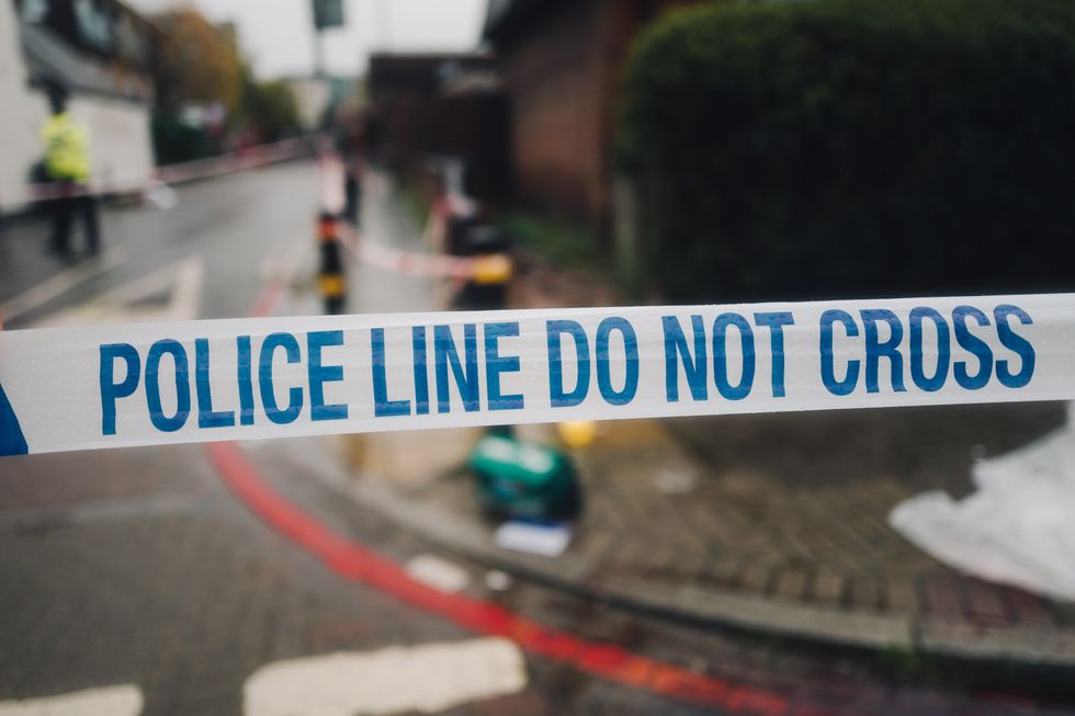Photo of the white and blue police cordon tape and the mess on the street in the background