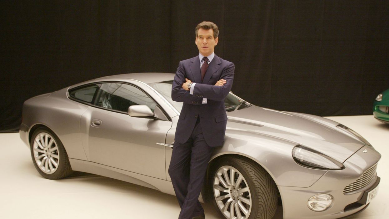 Pierce Brosnan poses with an Aston Martin V12 Vanquish at a press conference for Die Another Day