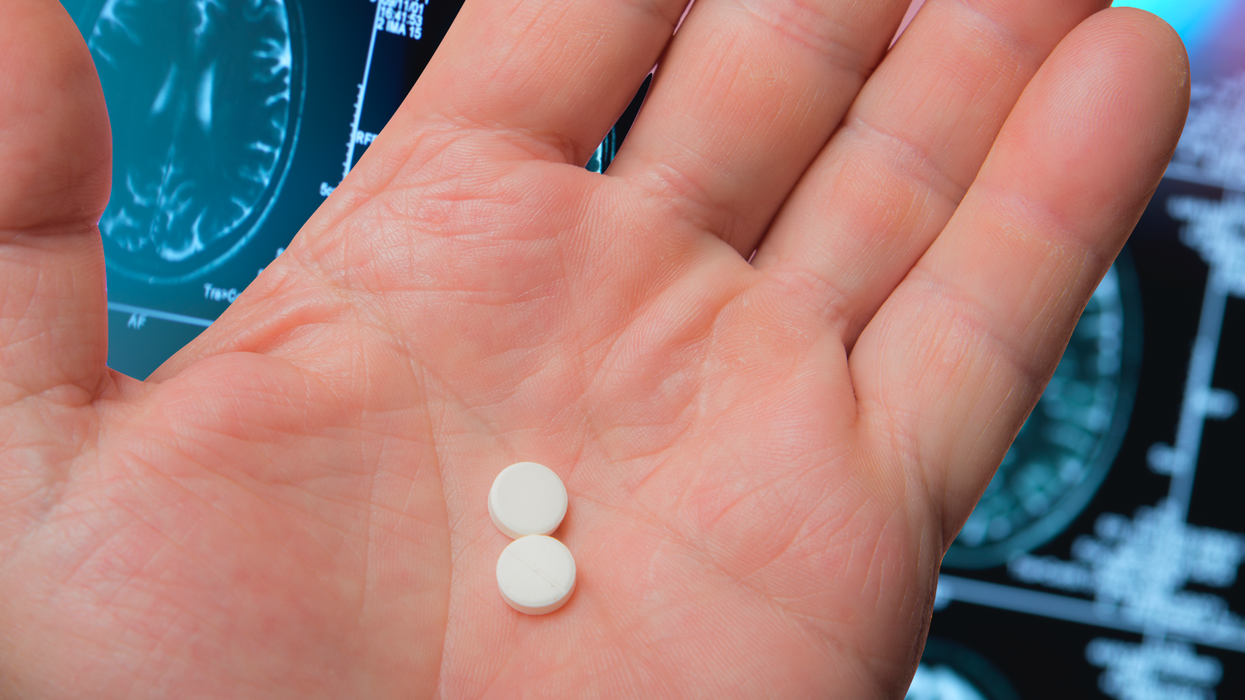Pill in hand in front of brain scan