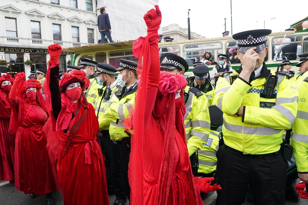 Police and demonstrators with a bus parked on London Bridge in central London during a protest by members of Extinction Rebellion. Picture date: Tuesday August 31, 2021.