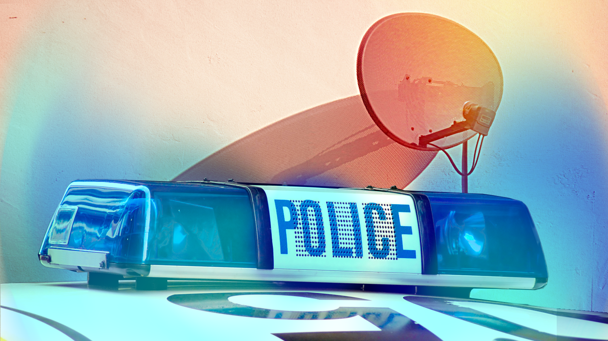 police car with flashing sirens and sky tv satellite dish affixed to a wall in the background