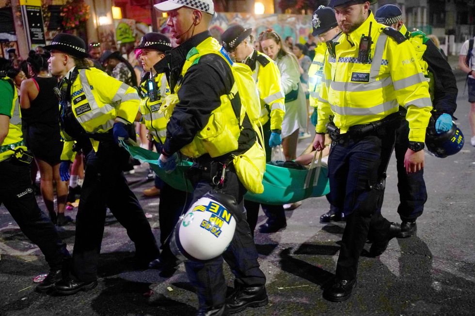 Police carry a person on a fabric stretcher during the family day at the Notting Hill Carnival in London, which returned to the streets for the first time two years after it was thwarted by the pandemic. Picture date: Sunday August 28, 2022.