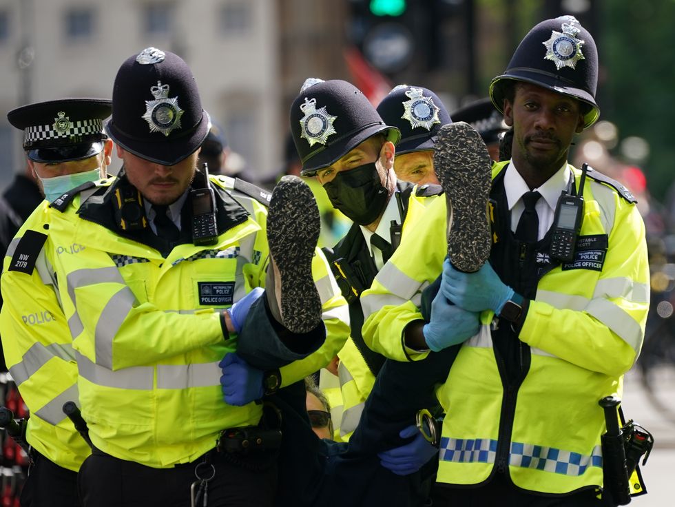 Police carry away a demonstrator during a protest by members of Extinction Rebellion on Whitehall, in central London. Picture date: Tuesday August 24, 2021.