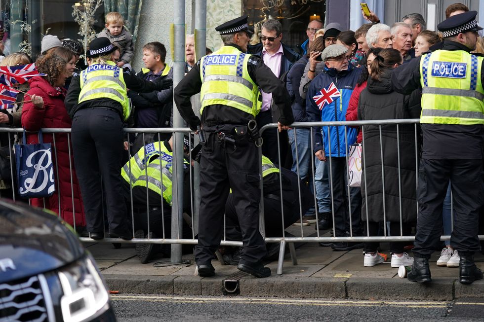 Police detain a protester who is believed to have egged the King and Queen Consort.