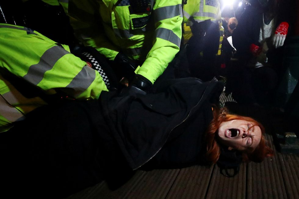Police detain a woman as people gather at a memorial site in Clapham Common Bandstand, following the kidnap and murder of Sarah Everard, in London, Britain March 13, 2021. REUTERS/Hannah McKay
