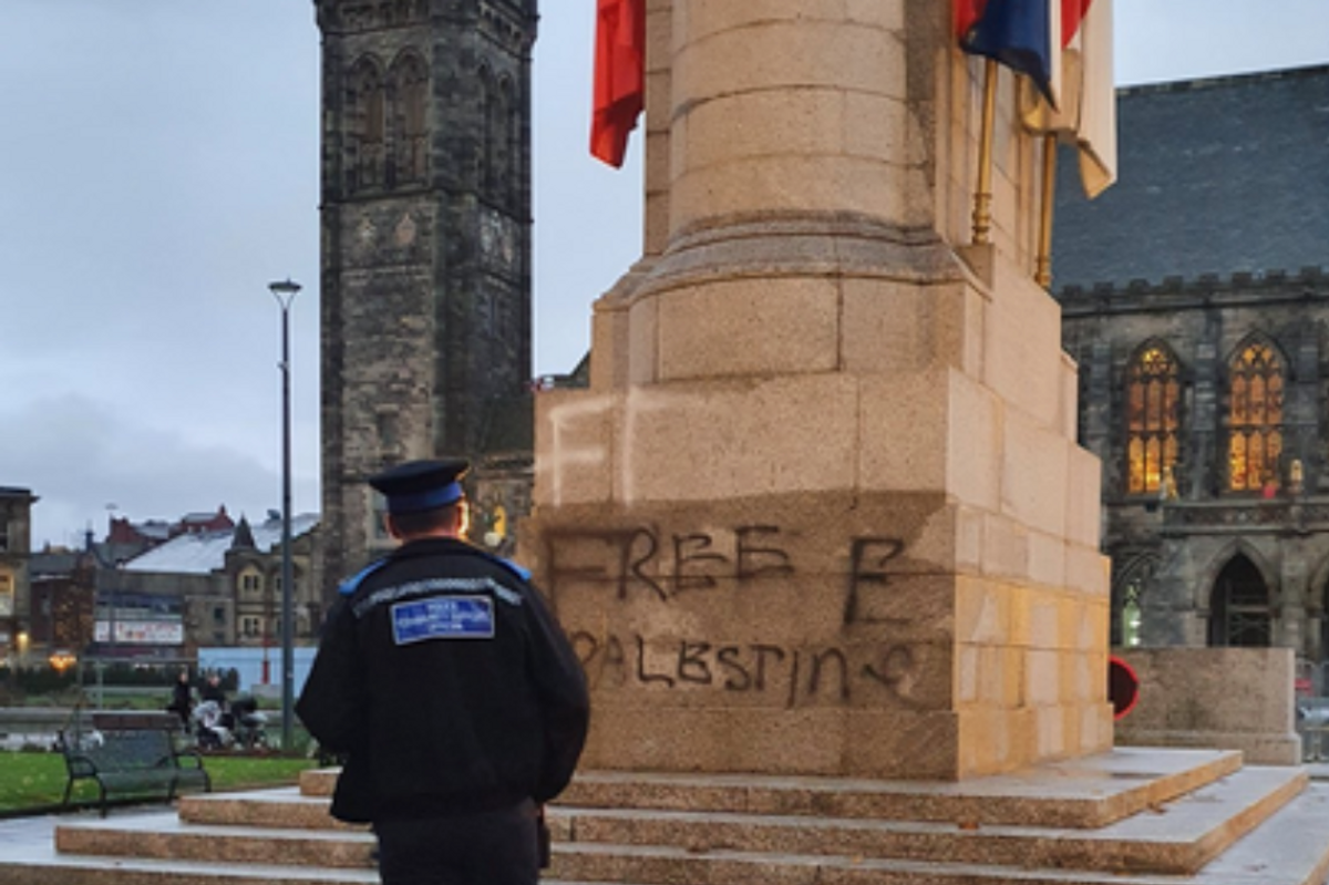 Police officer standing in front of vandalism on Rochdale Cenotaph