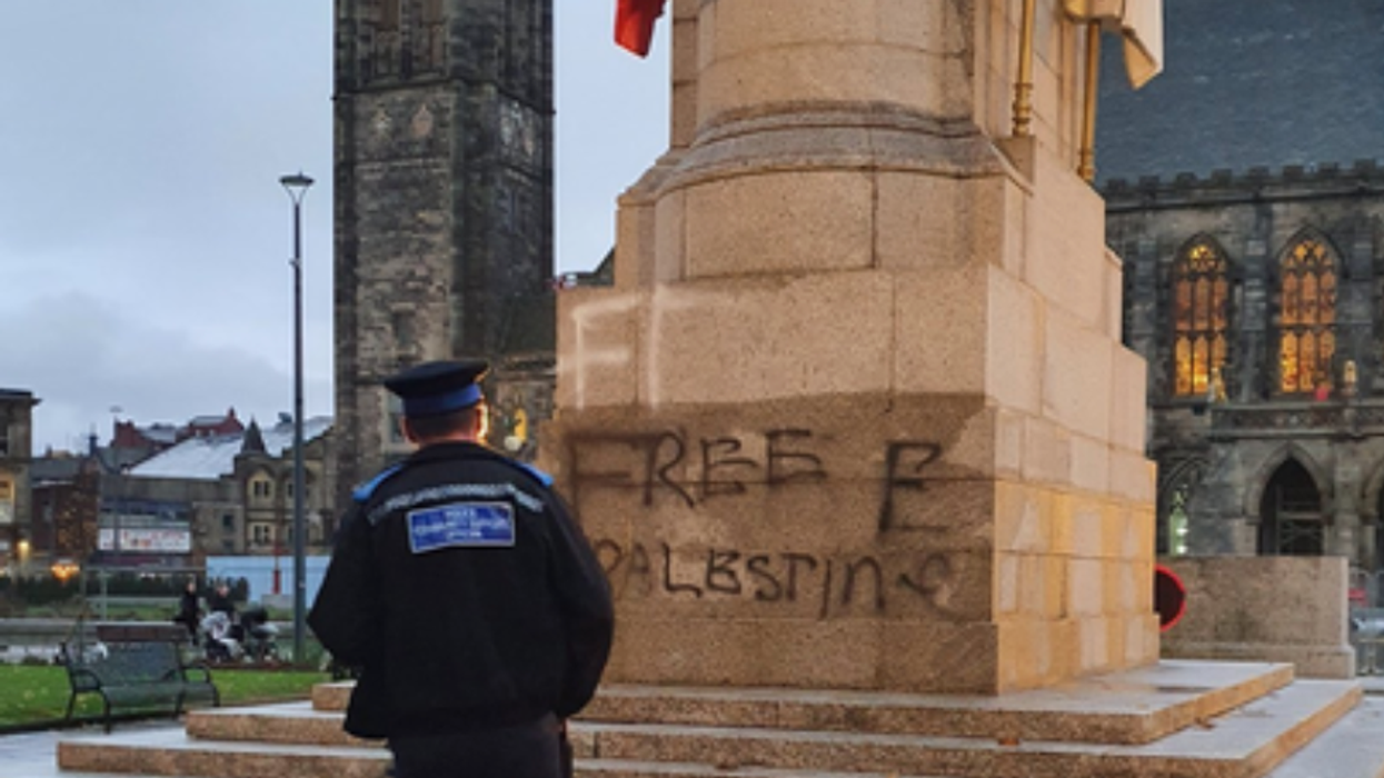 Police officer standing in front of vandalism on Rochdale Cenotaph
