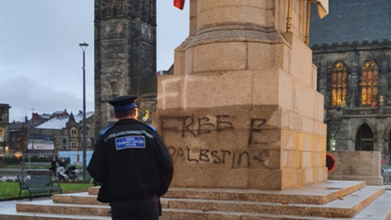 Police officer standing in front of vandalism on Rochdale Cenotaph