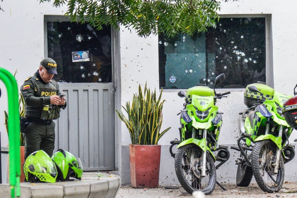 Police officer stands at damaged police hut which has been attacked with explosives in C\u00facuta
