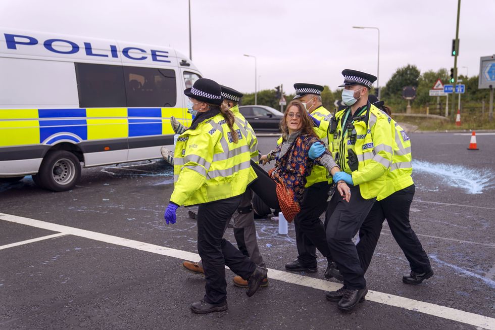 Police officers carry away a protester who had glued herself to a slip road at Junction 4 of the A1(M), near Hatfield.