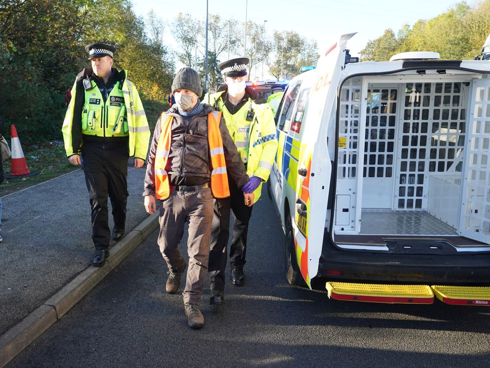 Police officers detain a protester at an Insulate Britain roadblock near to the the South Mimms roundabout at the junction of the M25 and A1. Picture date: Tuesday November 2, 2021.