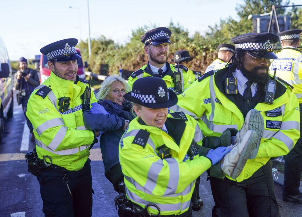 Police officers detain a protester from Insulate Britain occupying a roundabout leading from the M25 motorway to Heathrow Airport in London. Picture date: Monday September 27, 2021.