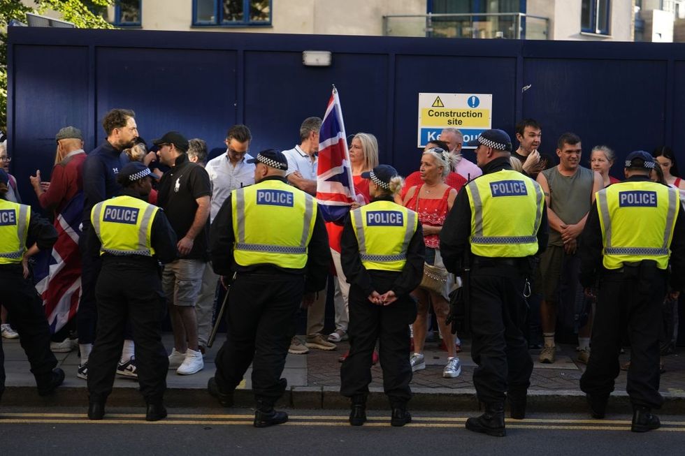Police officers form a barrier in front of counter-protesters separating them from the Stand Up to Racism rally outside the Britannia International Hotel in Canary Wharf