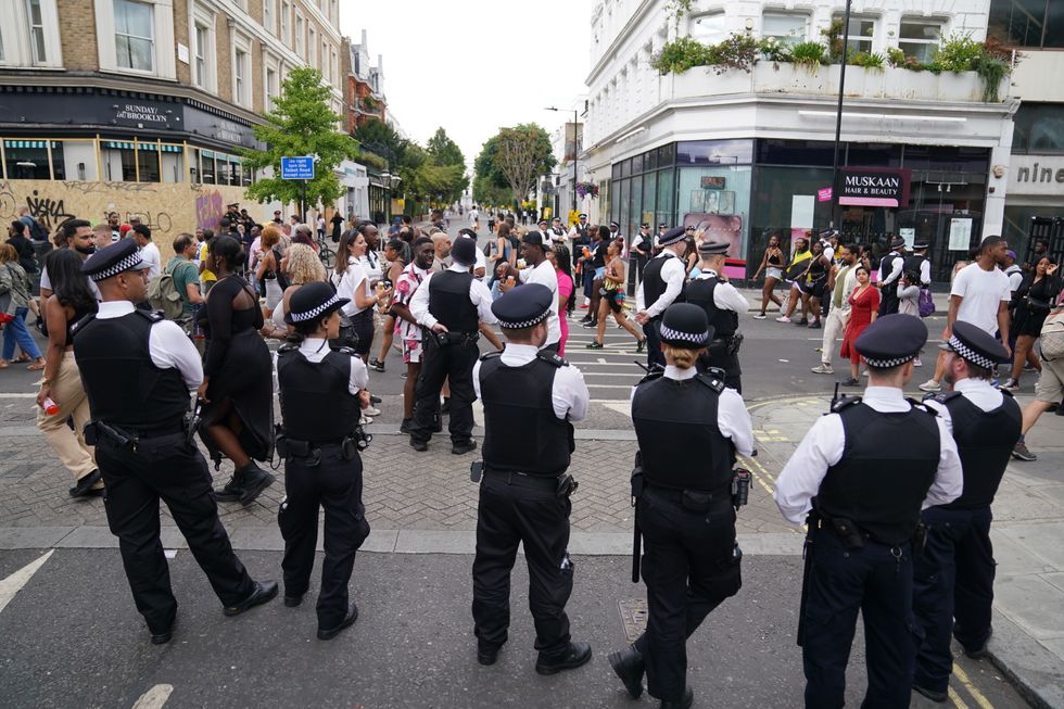 Police officers looking at revellers during the Notting Hill Carnival in London, which returned to the streets for the first time in two years after it was thwarted by the pandemic. Picture date: Monday August 29, 2022.