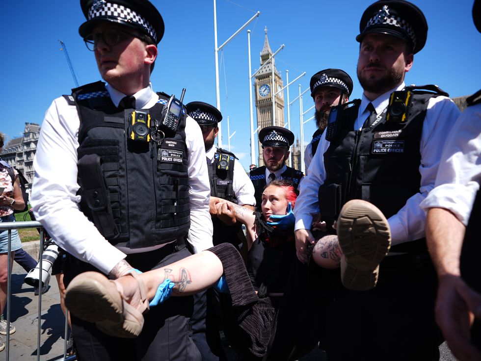 Police officers remove a person after they took part in a protest in Parliament Square, London, to call for de-proscription of Palestine Action