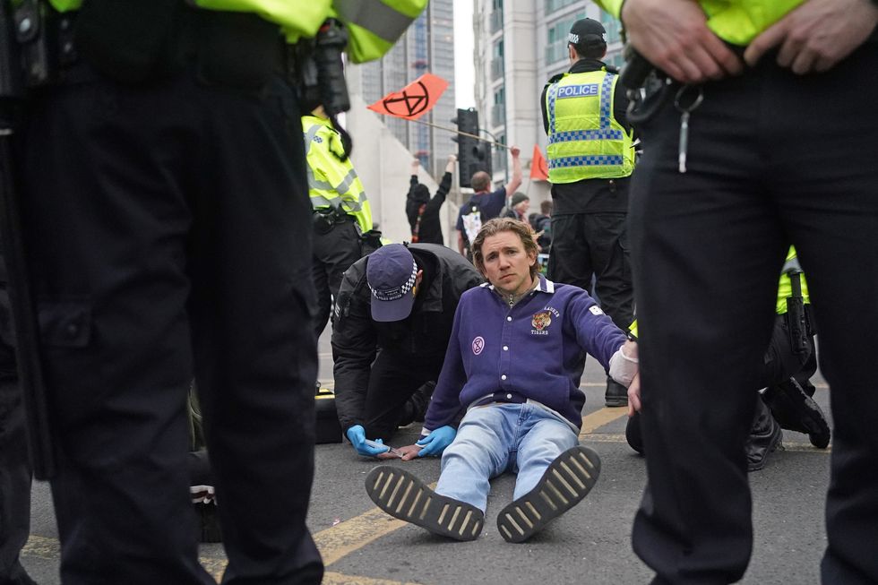 Police officers remove a protester glued to Vauxhall Bridge in central London. Picture date: Sunday April 10, 2022.