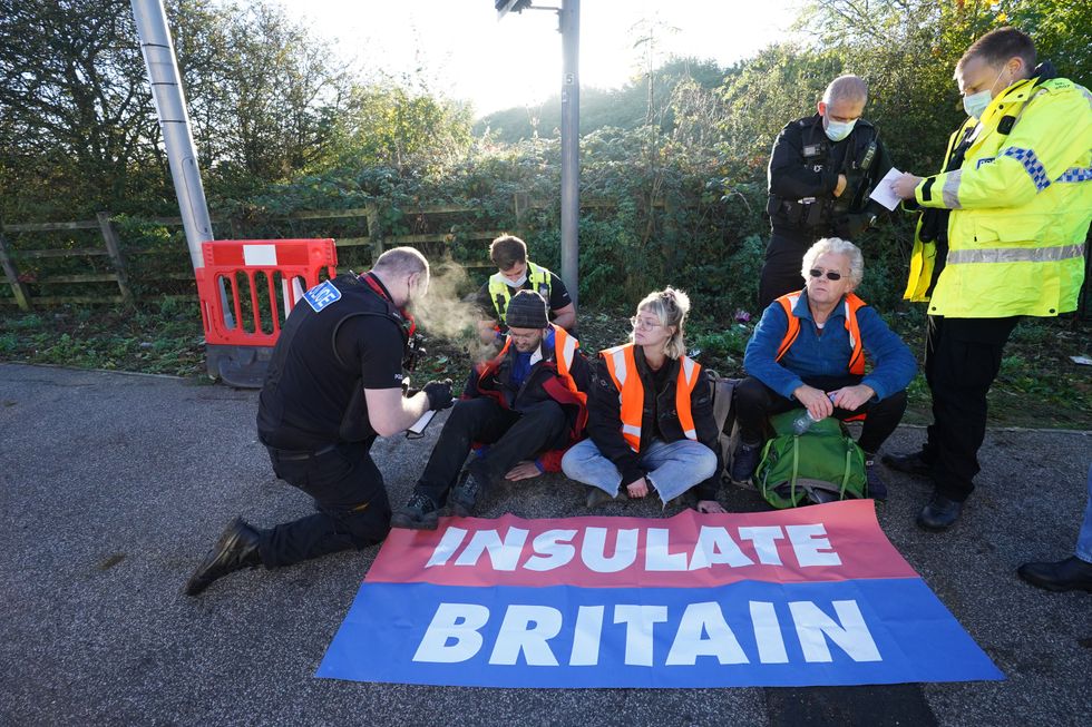Police officers speak to protesters at an Insulate Britain roadblock near to the the South Mimms roundabout at the junction of the M25 and A1. Picture date: Tuesday November 2, 2021.