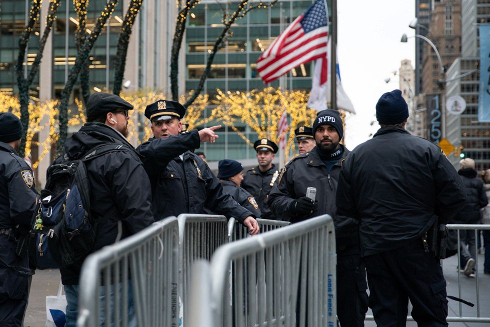 Police officers stand guard as people arrive to watch the 91st Rockefeller Center Christmas Tree Lighting Ceremony