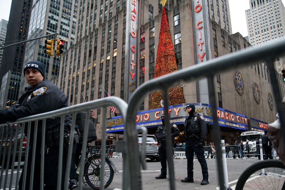 Police officers stand guard as people arrive to watch the 91st Rockefeller Center Christmas Tree Lighting Ceremony
