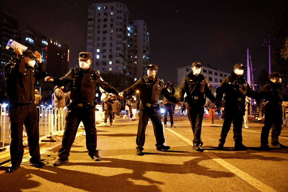 Police officers stand guard as people protest coronavirus disease (COVID-19) restrictions and hold a vigil to commemorate the victims of a fire in Urumqi, as outbreaks of the coronavirus disease continue, in Beijing, China, November 27, 2022. REUTERS/Thomas Peter