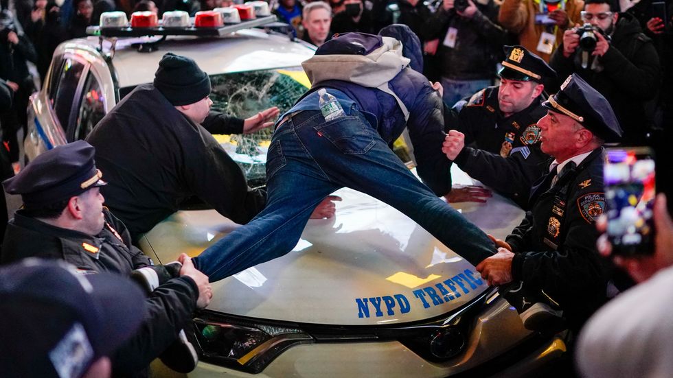 Police officers try to remove a protestor from a police vehicle, on the day of the release of a video showing police officers beating Tyre Nichols, the young Black man who died three days after he was pulled over while driving during a traffic stop by Memphis police officers, in New York, U.S., January 27, 2023. REUTERS/Eduardo Munoz