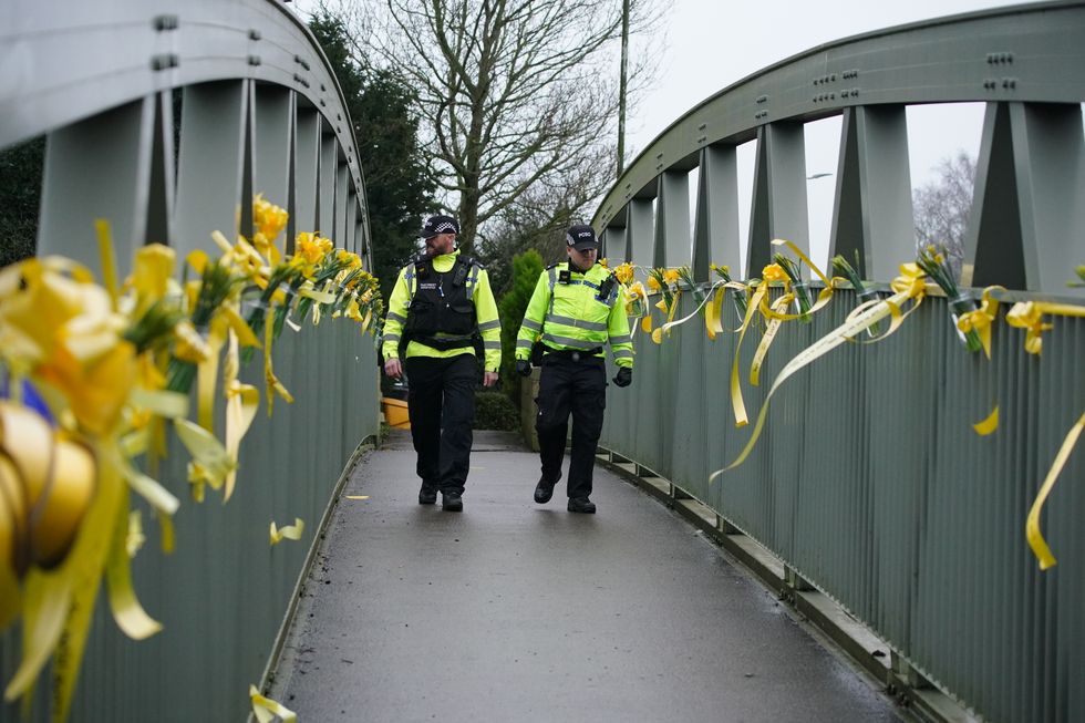 Police officers walk past yellow ribbons and messages of hope tied to a bridge for Nicola Bulley over the River Wyre in St Michael's on Wyre, Lancashire, as police continue their search for Ms Bulley, 45, who vanished on January 27 while walking her springer spaniel Willow shortly after dropping her daughters, aged six and nine, at school. Picture date: Thursday February 16, 2023.