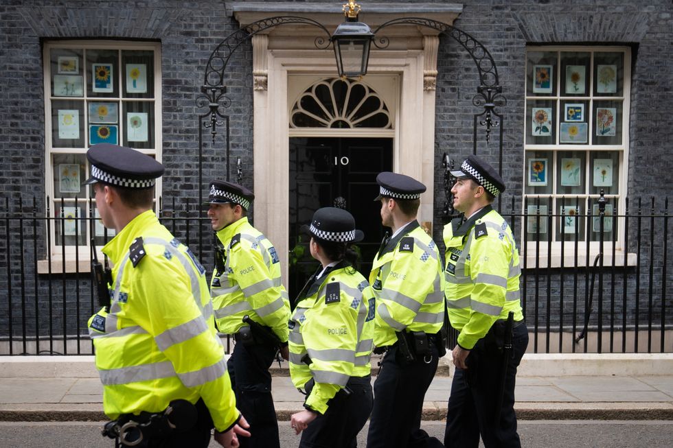 Police officers walk through Downing Street, in Westminster, London, during a protest outside the gates.